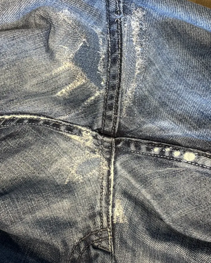 The same seam junction with both holes darned closed in tonal thread, the surface flat and continuous.