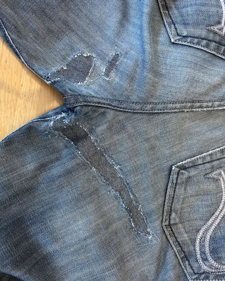 The same jeans with both splits backed by darker denim patches stitched in from behind.