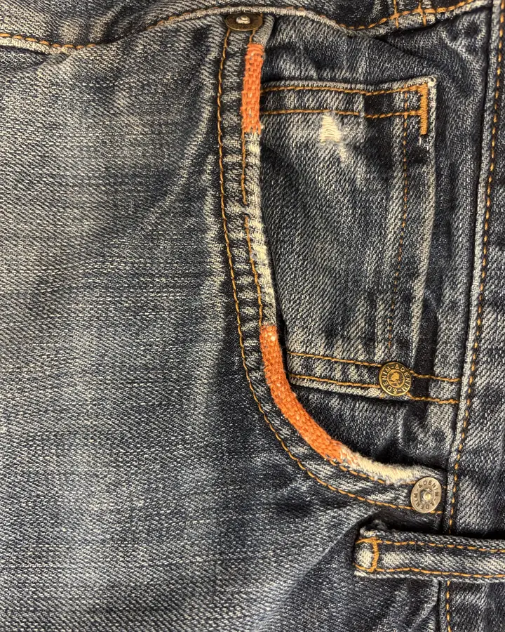 The same pocket opening wrapped and bound along its length in bright orange thread.