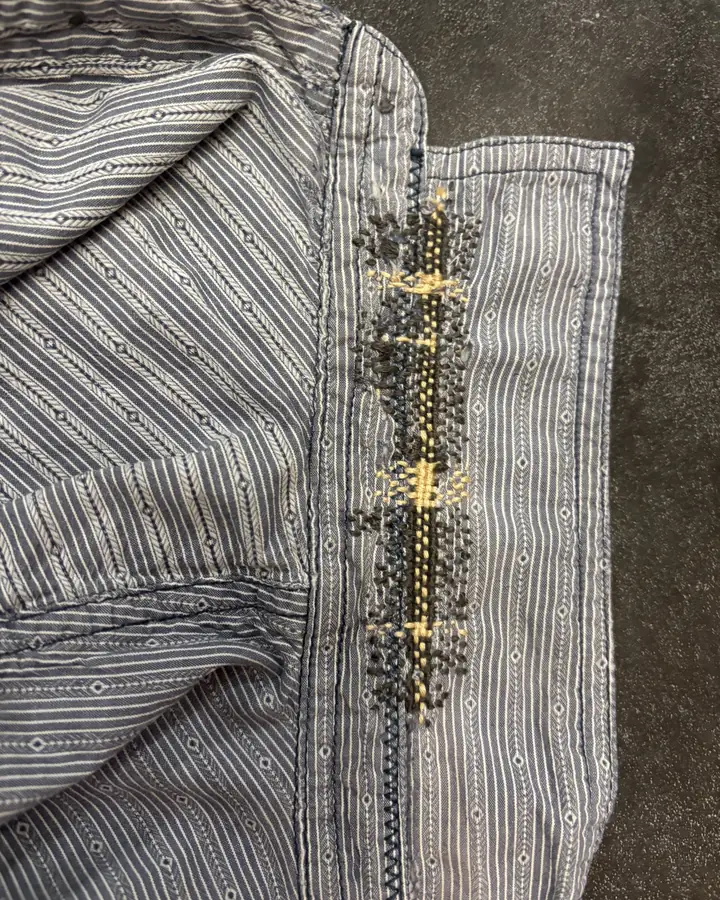 The same placket rebuilt and covered with a band of black and gold embroidery running its length.
